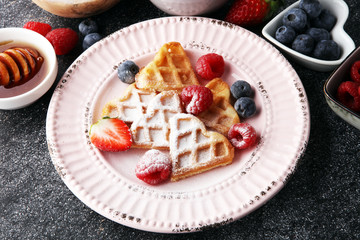 Traditional belgian waffles with fresh fruit and powder sugar on wooden board