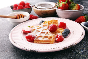 Traditional belgian waffles with fresh fruit and powder sugar on wooden board