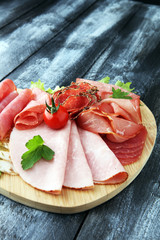 Food tray with delicious salami, pieces of sliced ham, sausage, tomatoes, salad and vegetable - Meat platter with selection