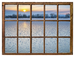 sunset over frozen lake -  window view