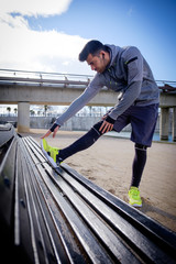 Young athlete man stretching after running in a park