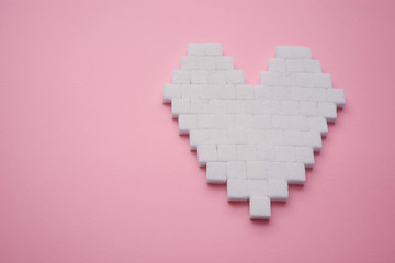 Heart made of cubes of sugar. Sugar kills. Pink background.