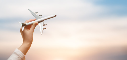 kid holding airplane in hands and flying over the sunset background