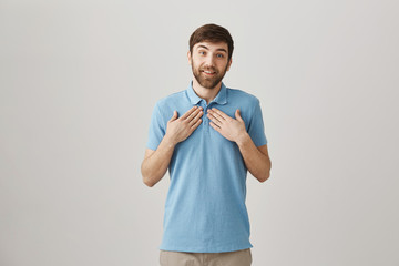 Pleasant charming european male with beard and moustache bring hands towards chest with lovely...