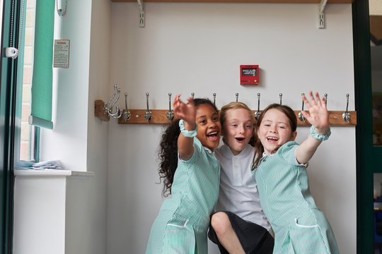 Three Schoolgirls Having Fun In Primary School Cloakroom