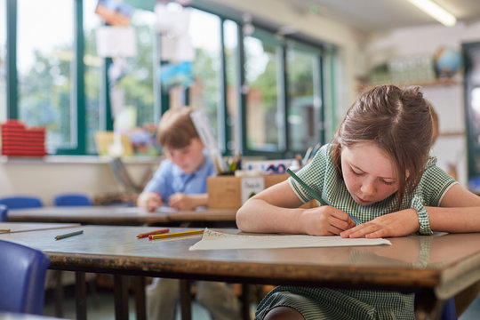 Schoolgirl writing in classroom lesson in primary school