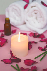 Obraz na płótnie Canvas Scented candle and dry petals on pink background; wellness or spa background