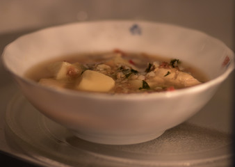 A bowl of soup is going to be heated in a microwave oven