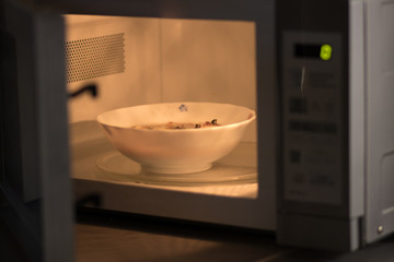 A bowl of soup is going to be heated in a microwave oven