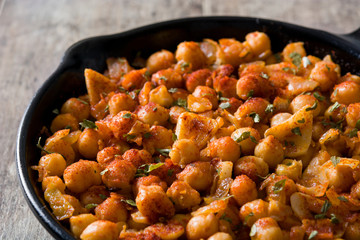 Close up fried spicy chickpeas in frying pan on wooden table