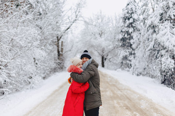 Fototapeta na wymiar A beautiful family couple walking on a snowy road in the woods