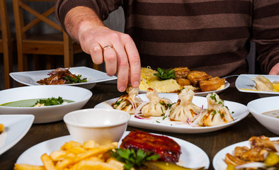 man's hand takes khinkali from a plate. 