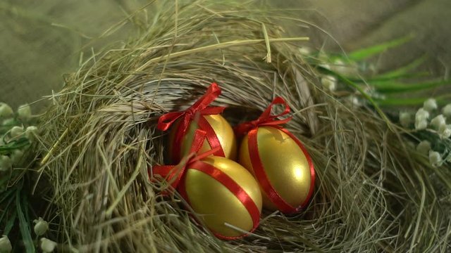 Painted, golden eggs with red ribbons in the nest