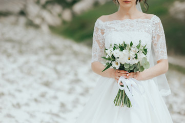 beautiful bouquet of different colors in the hands of the bride in a white dress