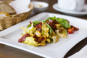 Raw food salad of fresh vegetables and sun-dried tomatoes in a white plate on the table