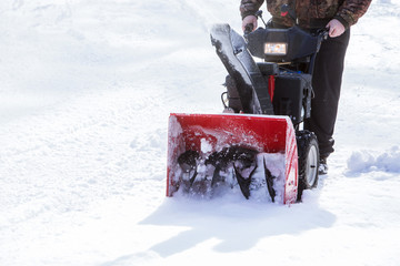 man cleans snow with a snow-removing machine
