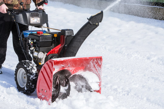 man cleans snow with a snow-removing machine