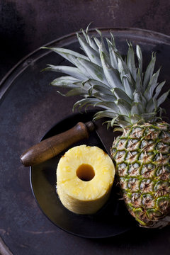 Stack of pineapple slices, whole pineapple and cleaver