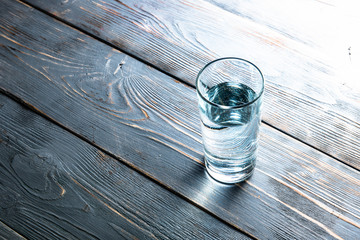 glass of crystal-clear water on a wooden background top view