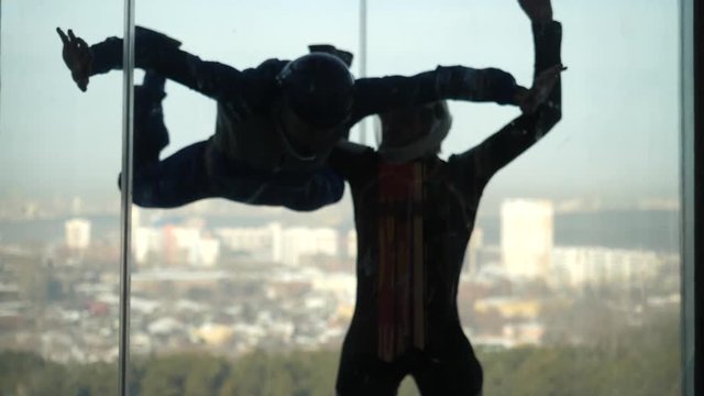 Male instructor helps man to fly inside air-tube. Training flight in an air tube with an instructor