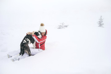 Woman playing with her dog in the snow on a winter day