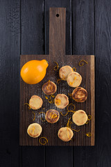 Dark oak cutting board with homemade cookies and lemon above view copyspace