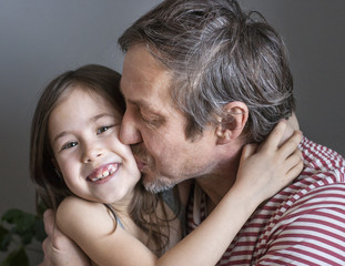 grandfather kisses his beloved granddaughter, holding her in his arms