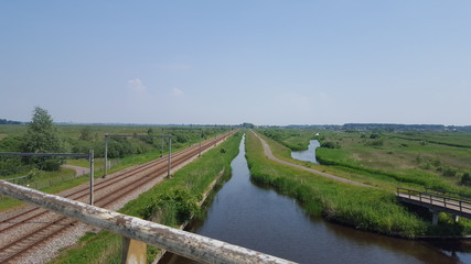 Fototapeta na wymiar Railroad next to a river and green areas