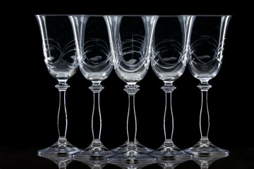 five wine glasses placed in a row on black background