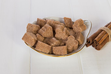 Brown sugar cubes with cinnamon in a bowl on a white wooden table