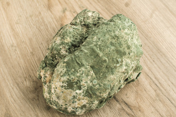 Moldy and musty wheat bread loaf on wooden background