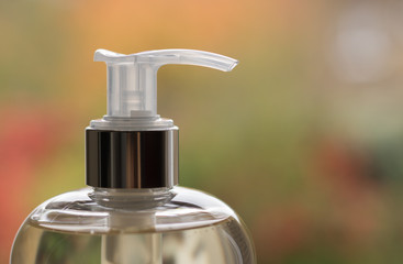 Close-up: image of shampoo or liquid soap in a clear bottle with a dispenser. Liquid have a light...