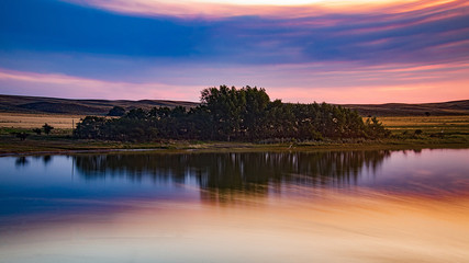 Pequeño bosque reflejado en el lago al atardecer