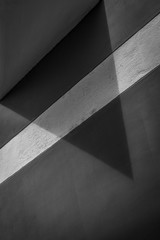 House wall detail with shade, black and white.  Triangular shadow and white painted strip on the wall of the house.