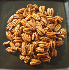 A bunch of nuts pecan on a black plate. Close-up photo 