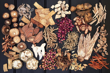 Large chinese herb selection used in traditional herbal medicine on dark wood background. Top view.