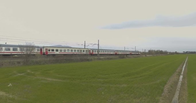 Treno bianco e rosso in transito in un prato verde