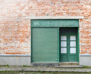 Fototapeta na wymiar Old abondoned shop with green metal roller shutter. Closed business