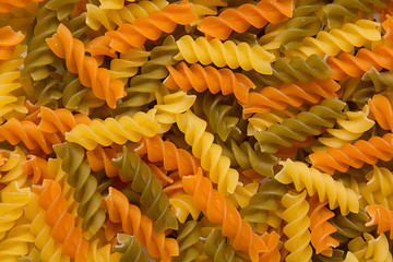 Italian fusilli pasta salad with pesto genovese, colorful tomatoes and basil leaves on dark wooden...