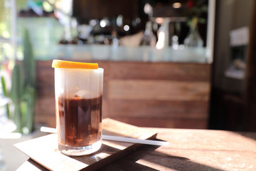 Ice black coffee with orange on wood background
