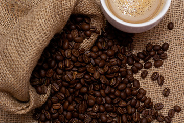 A cup of latte coffee and coffee beans.