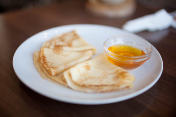 Delicious pancakes with honey on plate on table
