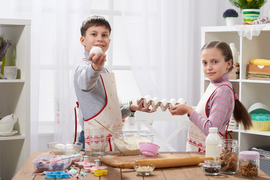 Child girl and boy cooking in home kitchen, hold eggs in the hands