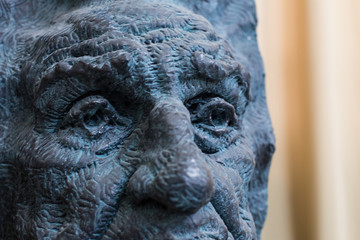 Close up of a face dark painted statue with blue details of an old man