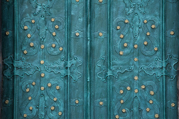 Weathered turquoise catholic Cathedral metal doors with ornaments and decorations texture background