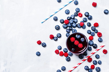Iced fruit tea with blueberry, raspberry and ice in glass, top view