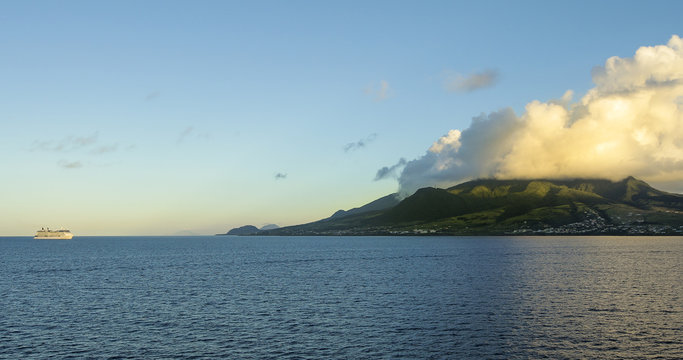 Cruise ship floating off the coast of St Kitts as sunlight hits the mountains.