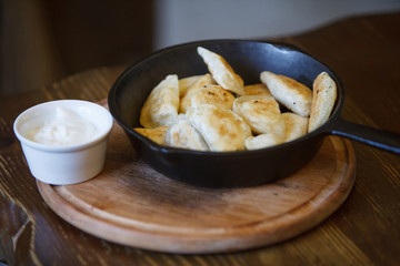Pan-fried Vareniks in a frying pan. Sour Cream. Delicious lunch