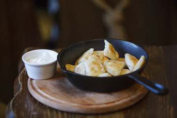 Pan-fried Vareniks in a frying pan. Sour Cream. Delicious lunch