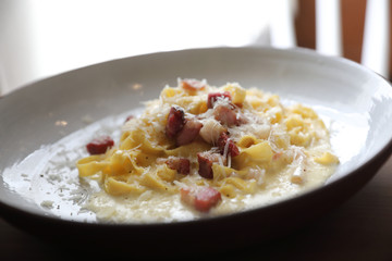spaghetti carbonara white sauce with bacon on wood background in restaurant